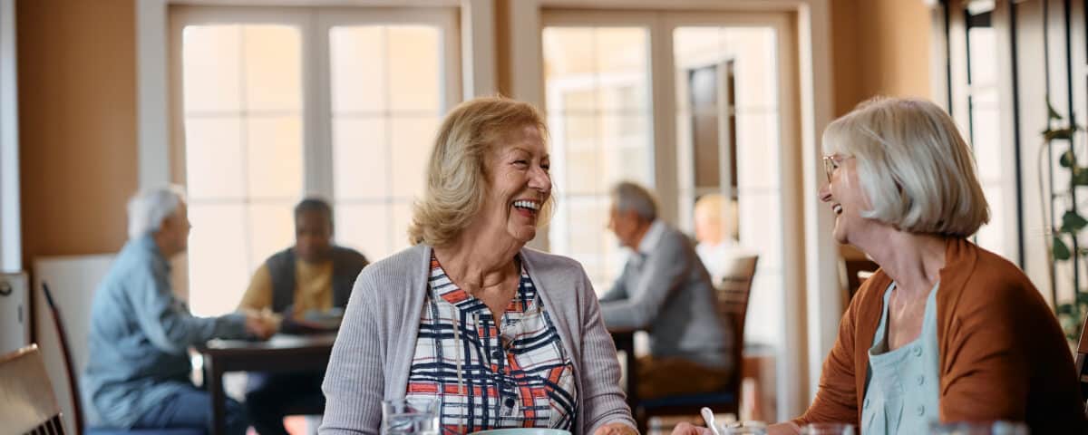 Happy senior women talk while having lunch at nursing home.