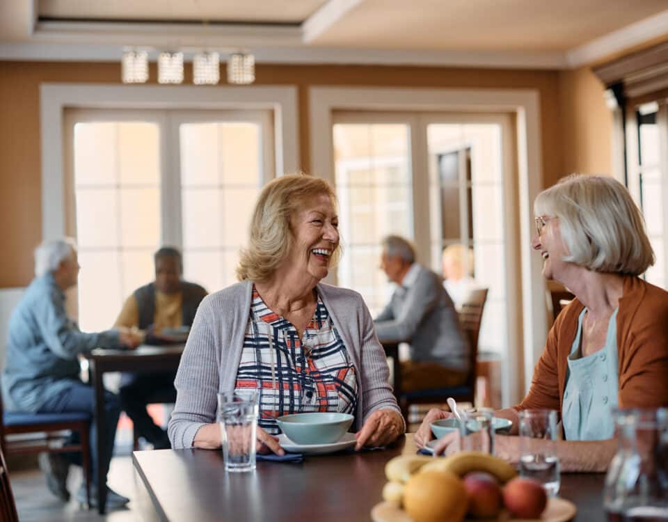 Happy senior women talk while having lunch at nursing home.